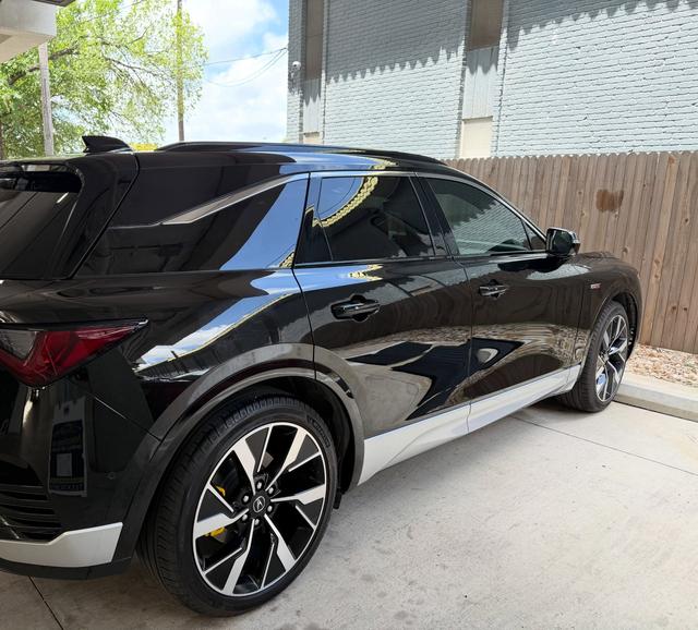Rear three-quarter view of the black Acura ZDX after the hand wash, with deep gloss along the doors and silver lower trim
