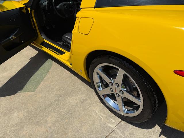 Corvette door open over a clean black sill, with the yellow rear fender and chrome wheel freshly cleaned