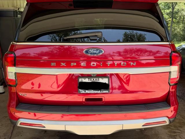Rear of the red Expedition with clean taillights, chrome Expedition lettering, and a freshly washed tailgate