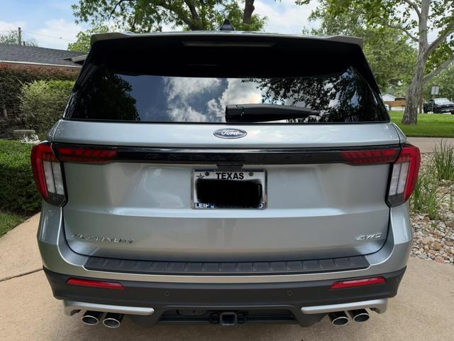 Rear of the silver Ford Explorer Platinum after the wash, with clean taillights, badges, and quad exhaust tips