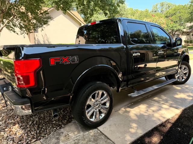Rear quarter of the black F-150 showing the red FX4 badge, clean taillight, and glossy bedside after the detail