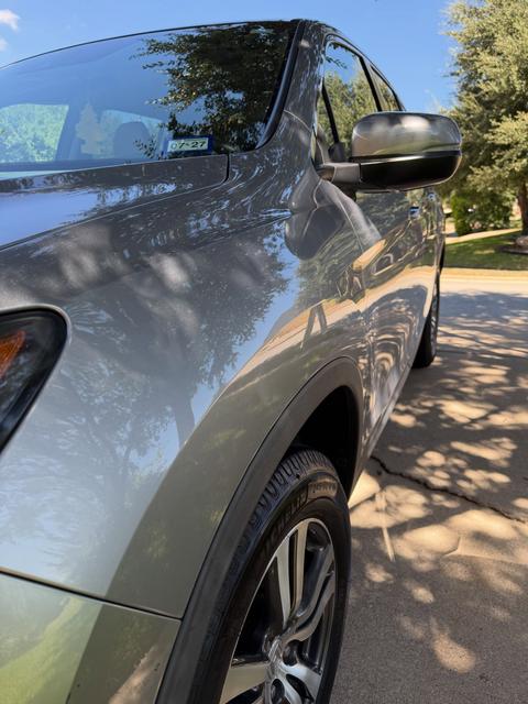 Close view of the Honda Pilot front fender and door after washing, with tree reflections in the silver paint