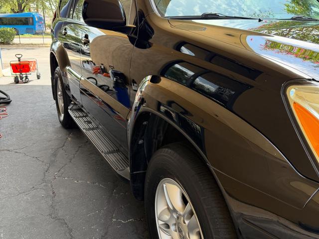 Freshly detailed black paint on the Lexus GX470 fender reflecting trees and sky