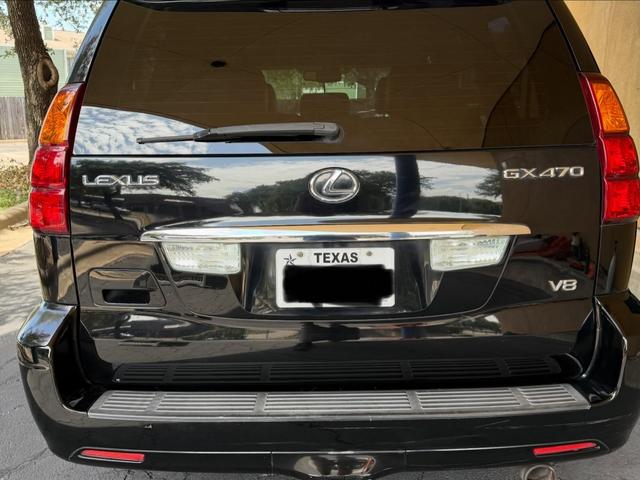 Tailgate of the Lexus GX470 with polished chrome trim, crisp LEXUS and V8 badges, and clouds mirrored in the black paint