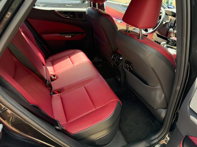 Rear seats of the black Lexus NX 350 from the passenger door, with clean red leather and fresh carpet