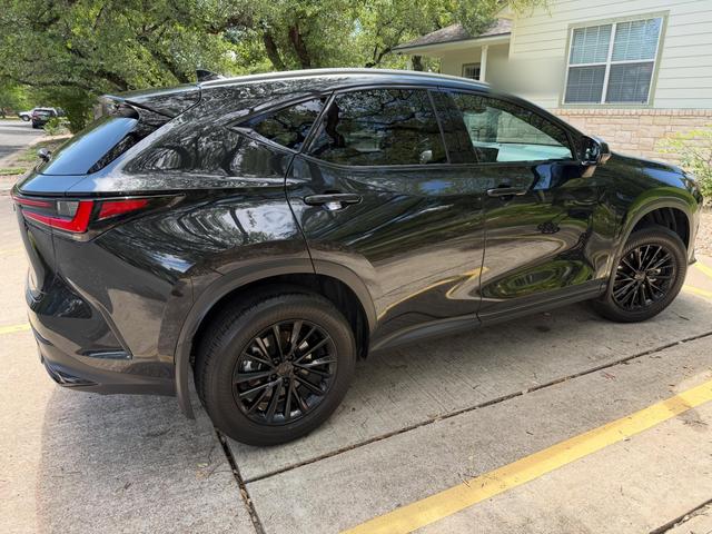 Rear three-quarter view of the black Lexus NX 350 after the detail, with tree reflections in the freshly washed paint