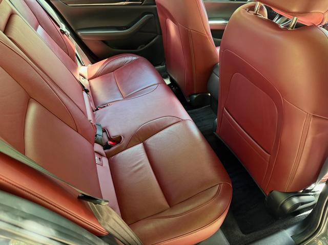 Red leather rear bench of the Mazda 3 Carbon Edition from the passenger side after the detail, with clean floor mats