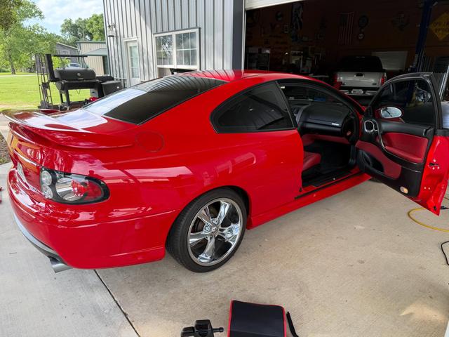 Red 2006 Pontiac GTO with the driver door open, clean red paint and red interior side by side