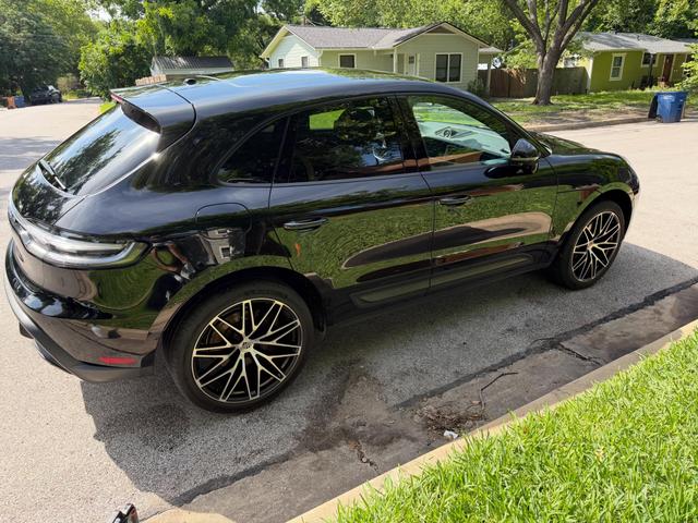 Black Porsche Macan from the rear three-quarter after a hand wash, with mirror-like paint and two-tone wheels on a sunny street