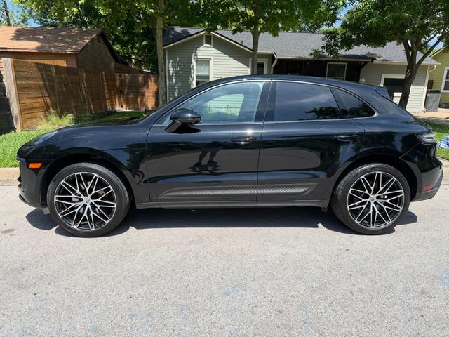 Side profile of the Porsche Macan at the curb after the detail, with clean glass, glossy doors, and dressed tires