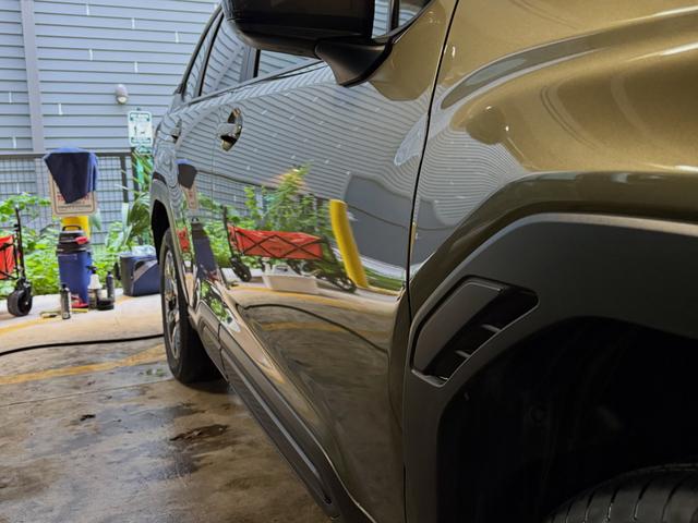 Glossy green paint on the Subaru Forester reflecting the parking garage