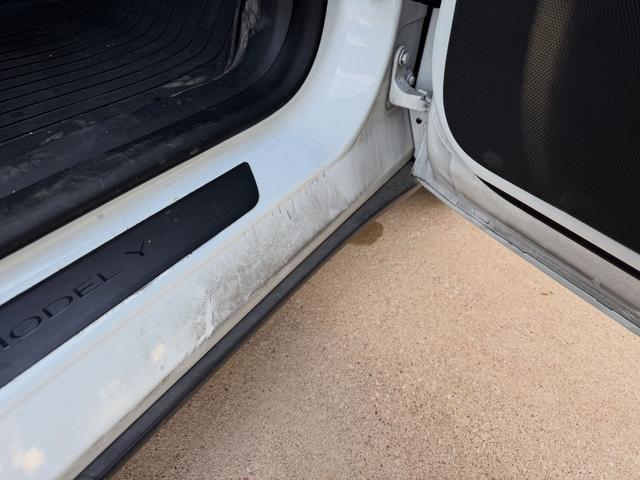 Before: grimy Tesla Model Y door sill and floor edge with scuffed white paint