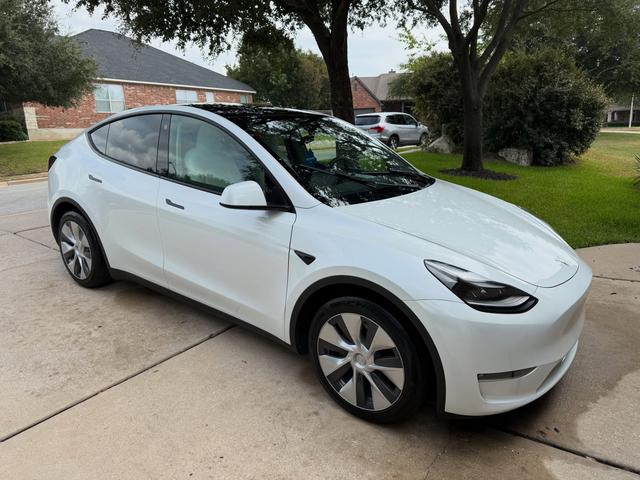 White 2023 Tesla Model Y in a Cedar Park driveway after a hand wash, with glossy paint and clean aero wheels