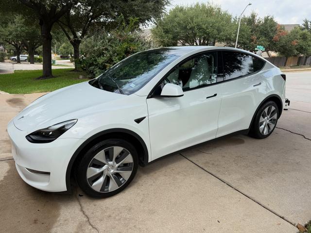 Driver side of the white Tesla Model Y after the wash, showing clean glass, black trim, and spotless wheels