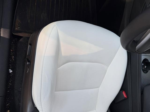 Before: Model Y driver seat with marks on the white leather and debris on the floor mat