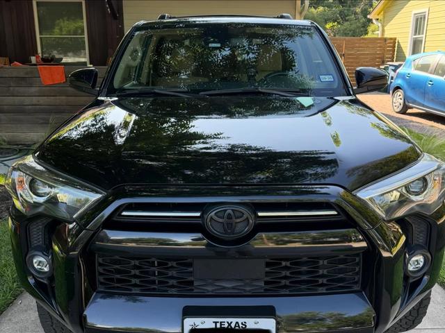 Front grille and hood of the Toyota 4Runner after the hand wash, with trees reflecting cleanly in the black paint