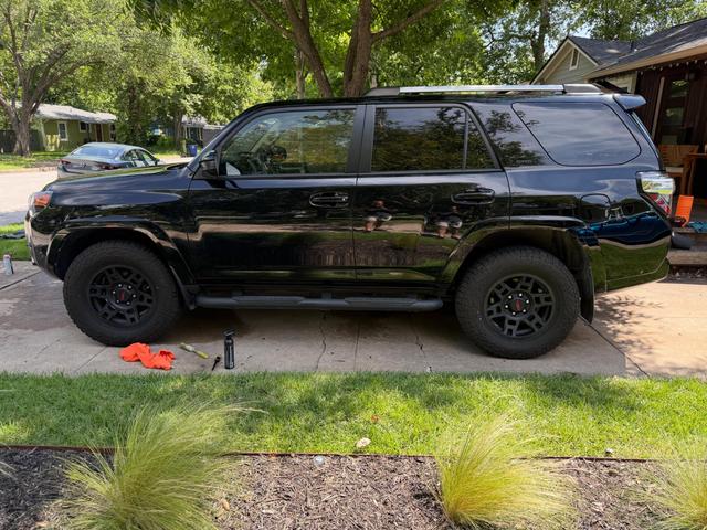 Side profile of the black Toyota 4Runner parked at the curb, with even gloss from the front fender to the rear bumper