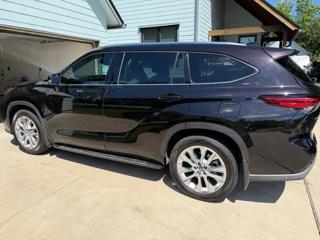 Black Toyota Highlander Limited side profile with reflective, freshly washed paint and clean chrome wheels