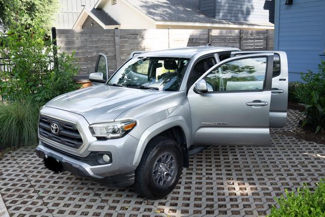 Silver Tacoma with both passenger-side doors open after the detail, showing the clean cab and polished body