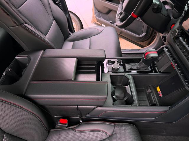 Wide center console and shifter of the Toyota Tundra wiped clean, with black leather seats on either side