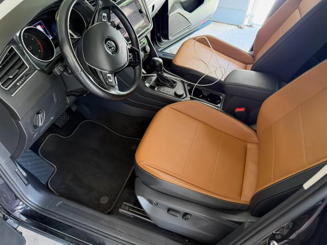 Tiguan driver seat after the interior detail, with saddle-brown leather, clean floor mats, and a wiped-down console