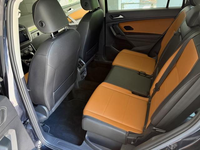 Rear bench of the Tiguan from the driver-side door after a deep vacuum, with brown leather and black floor carpet