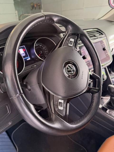 Steering wheel and digital gauge cluster of the Tiguan after a wipe-down, with the VW badge and controls free of fingerprints